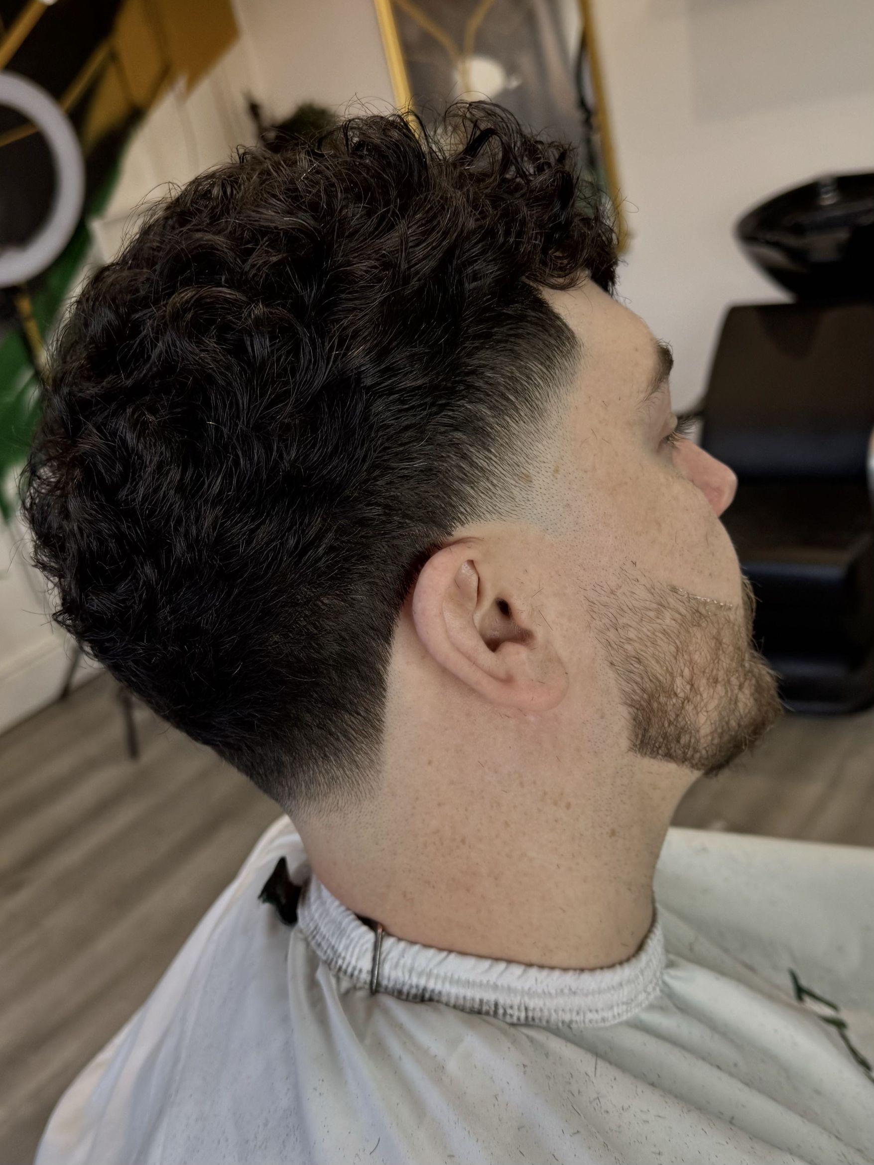 Curly skin fade haircut with sharp beard line